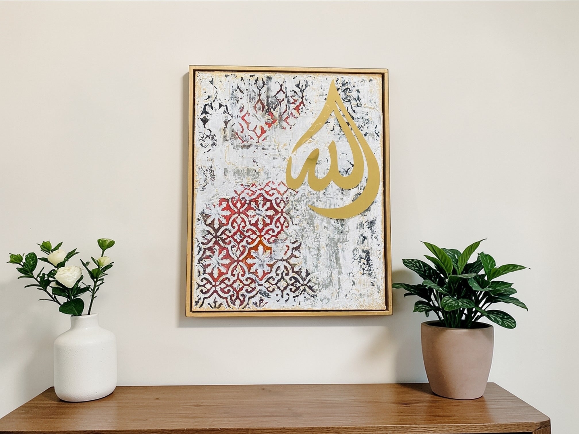 Decorative wall art with Arabic calligraphy on a wooden shelf with plants and a vase.