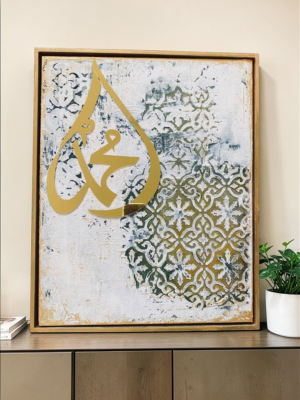 Decorative wall art with gold Arabic calligraphy on a textured background, framed in a wooden frame.