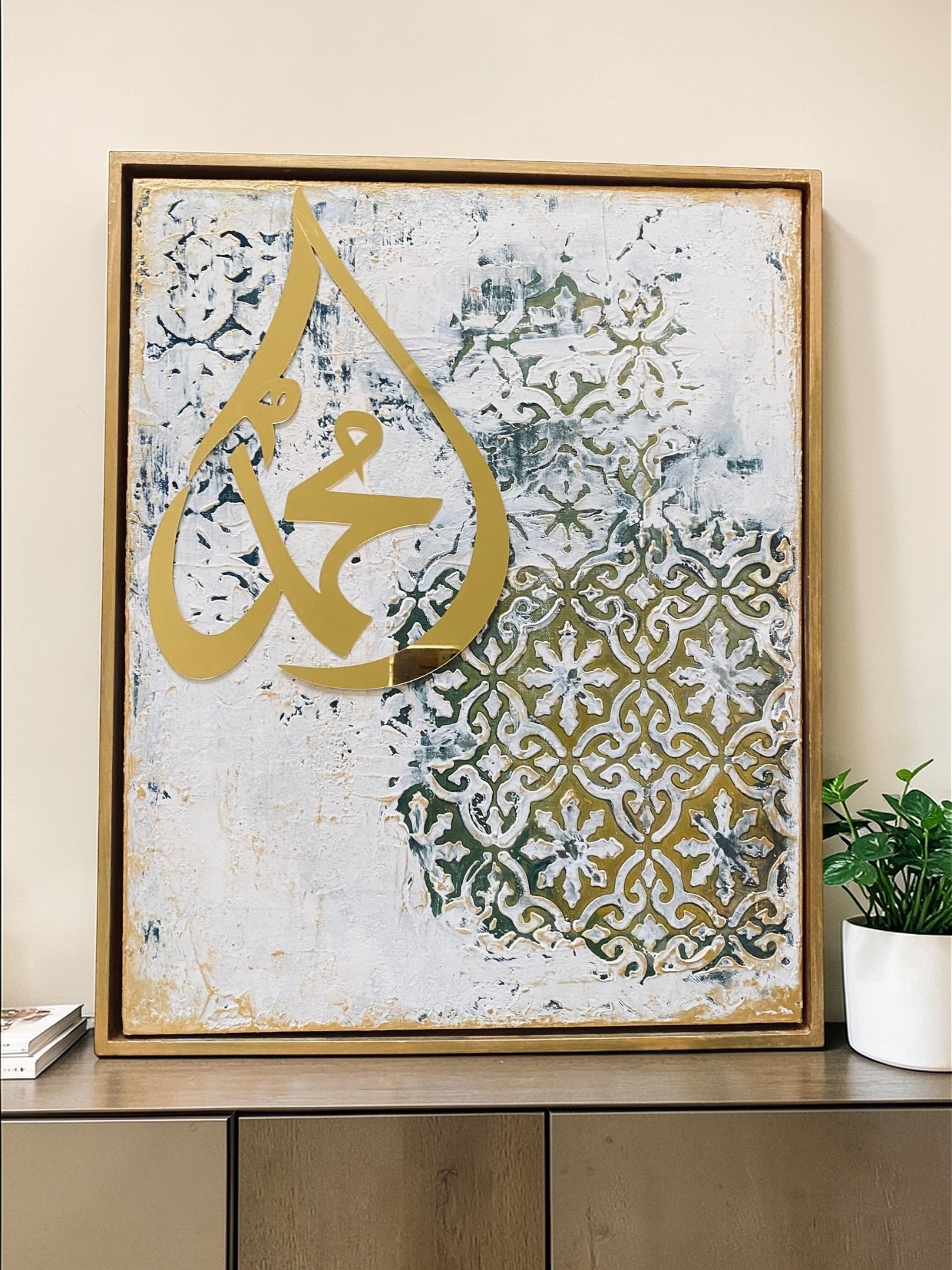 Decorative wall art with gold Arabic calligraphy on a textured background, framed in a wooden frame.
