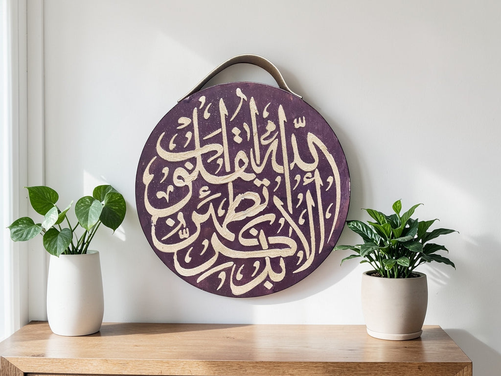Decorative circular sign with Arabic calligraphy on a wooden surface with two potted plants.